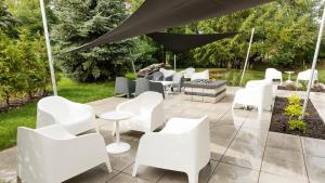 a patio with white chairs and a fire pit at Hotel Sepia in Quebec City