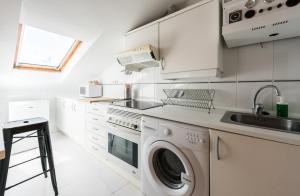 a white kitchen with a washing machine and a sink at El Tribunal de Barceló in Madrid