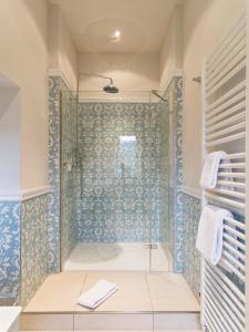ein Bad mit einer Dusche und blauen Fliesen in der Unterkunft Gästehaus Schloss Saareck in Mettlach
