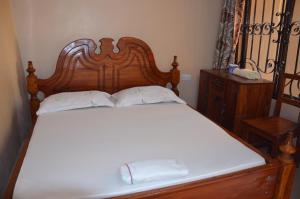 1 cama con cabecero de madera y 2 almohadas blancas en Lunguya Lodge, en Dar es Salaam