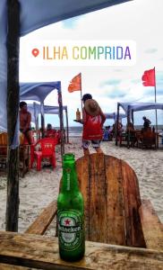 Una botella de cerveza sentada en una mesa en la playa en Apartamentos PraiaMar, en Ilha Comprida