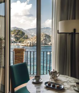 a dining room table with a glass of water at Villa Sant'Andrea, A Belmond Hotel, Taormina Mare in Taormina