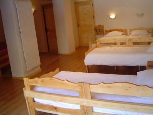 four beds in a room with wooden floors at Hotel Les Chalets in Brides-les-Bains