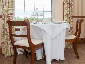a dining room table with a white tablecloth and two chairs at Poole Farm in Launceston
