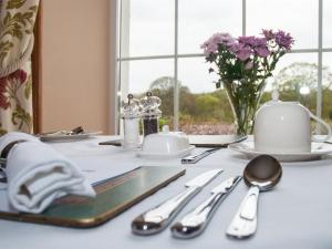 a white table with silverware and a vase of flowers at Poole Farm in Launceston