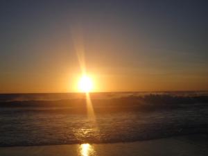 einen Sonnenuntergang über dem Meer mit der Sonne am Himmel in der Unterkunft Apartamento Jamesson Cabo Frio in Cabo Frio