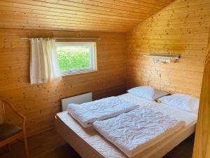 a bed in a wooden room with a window at Hummingen Camping hus 1 in Dannemare