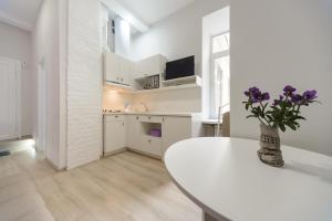 a white kitchen with a table and a vase with purple flowers at Bessarabka Apartments in Kyiv
