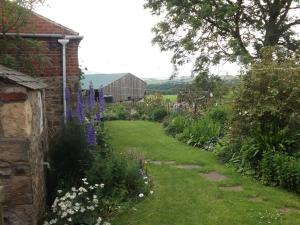 a garden with purple flowers and a brick building at Hillis Close Farm in Haltwhistle