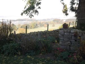 eine Steinmauer mit einem Zaun und einem Feld in der Unterkunft Hillis Close Farm Cottage in Haltwhistle