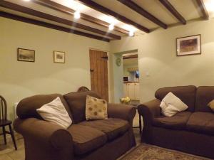 ein Wohnzimmer mit zwei braunen Sofas in einem Zimmer in der Unterkunft Hillis Close Farm Cottage in Haltwhistle