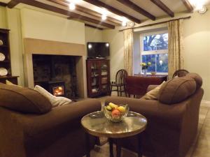 ein Wohnzimmer mit Sofas und einer Obstschale auf einem Tisch in der Unterkunft Hillis Close Farm Cottage in Haltwhistle + 17 Fotos