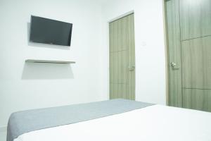 a bedroom with a bed and a tv on a wall at Hotel Ayenda House Concepción 1317 in Barranquilla