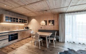 a kitchen with a wooden table and chairs at Presulis Hideaway Apartments & Restaurant in Völs am Schlern