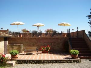 a patio with a bench and tables and umbrellas at Fattoria Pieve a Salti in Buonconvento