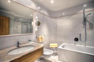 een badkamer met een wastafel, een bad en een toilet bij Hotel Ciasa Ai Pini in San Cassiano