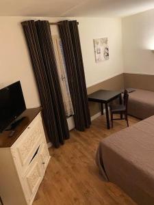 ein Hotelzimmer mit einem Bett und einem Schreibtisch mit einem TV in der Unterkunft Hôtel Restaurant Le Saint Gillois in Saint-Gilles
