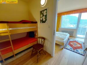 een slaapkamer met 2 stapelbedden en een stoel bij Apartment Nah Dran by FiS - Fun in Styria in Bad Mitterndorf