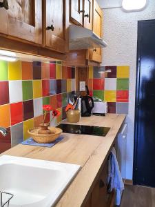 - une cuisine avec un comptoir, un évier et du carrelage coloré dans l'établissement les 3 marmottes - Les Arolles, à Bourg-Saint-Maurice