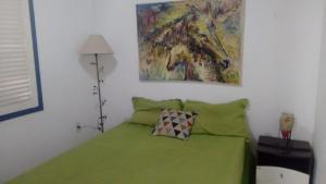 Casa em Cabo Frio في كابو فريو: غرفة نوم بسرير اخضر مع لوحة على الحائط