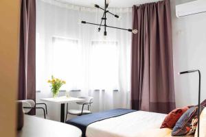 a bedroom with a bed and a table and a window at Beautiful Studio - Top Location - Netflix in Bucharest