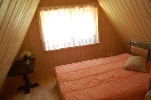 a small bedroom with a bed and a window at Gravas dzirnavas in Dārznieki