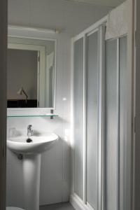bagno bianco con lavandino e specchio di Hotel Madrid de Sevilla a Siviglia