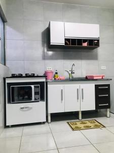 a kitchen with a stove and a microwave at Aconchego na Capital do Forró - Térreo in Caruaru