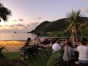 a group of people sitting at a table by the beach at Amami Lucky House - Vacation STAY 07619v in Amami