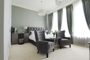 a bedroom with a bed and a couch and a chair at The Devon Court in Torquay