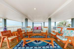 un portico con tavoli e sedie in legno e l'oceano di O' What A View a Gilchrist