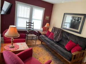 uma sala de estar com um sofá preto e cadeiras vermelhas em 1899 Inn em Deadwood