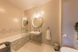 ein Badezimmer mit einem Waschbecken, einer Badewanne und einem Spiegel in der Unterkunft Vivando - Scandic Studio F + Parking in Bukarest