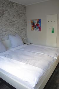 a large white bed with white sheets and pillows at City Pension Stadtlohn in Stadtlohn