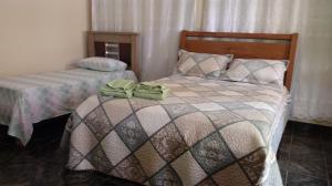 two beds in a bedroom with green towels on them at Casa com Flores in Pedra Azul