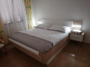 um quarto com uma cama grande com lençóis brancos e almofadas em Holiday House Maja em Podglavica
