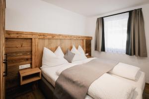 ein Schlafzimmer mit einem Bett mit weißen Kissen und einem Fenster in der Unterkunft Landhaus Holzer in Sankt Margarethen im Lungau