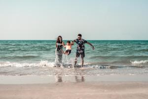 a family playing in the water at the beach at The Cove Rotana Resort - Ras Al Khaimah in Ras al Khaimah