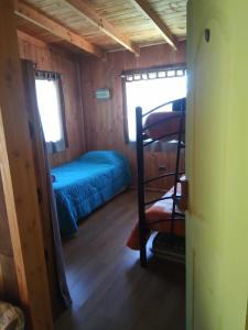 Habitación pequeña con cama y silla en Cabañas Wualmapu " acceso sólo vehiculos tipo camioneta, jeep o SUV", en Pucón