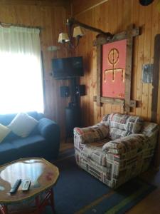 ein Wohnzimmer mit einem Sofa und einem Stuhl in der Unterkunft Cabañas Wualmapu " acceso sólo vehiculos tipo camioneta, jeep o SUV" in Pucón