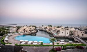 a large swimming pool surrounded by palm trees at The Cove Rotana Resort - Ras Al Khaimah in Ras al Khaimah