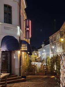een stadsstraat 's nachts met een verlicht bord bij ACSA INN in Craiova