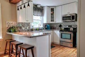 una cocina con armarios blancos y una barra con taburetes en ☆Oakley's Oasis: A Dharma Dwellings Designed Home☆ en Rochester