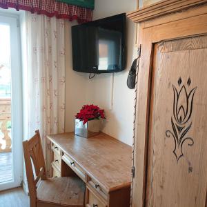 Pokój z drewnianym biurkiem i telewizorem na ścianie w obiekcie Alpenhostel "Das Besenhaus" w mieście Altenmarkt im Pongau