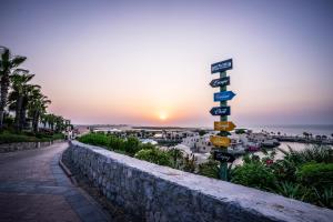 a street sign in front of the ocean at sunset at The Cove Rotana Resort - Ras Al Khaimah in Ras al Khaimah