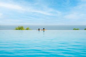 two people swimming in the water in the ocean at The Cove Rotana Resort - Ras Al Khaimah in Ras al Khaimah