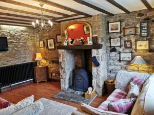 a living room with a stone wall with a fireplace at Pathways Cottage in Higham