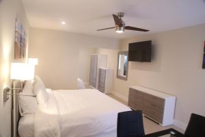1 dormitorio con cama blanca y ventilador de techo en Diane Oceanfront Suites en Hollywood