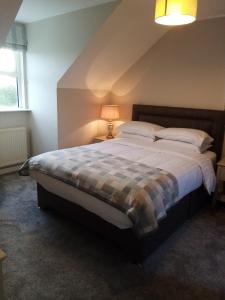 een slaapkamer met een groot bed en een geruite deken bij Dubhlinn House in Doolin