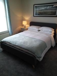 een slaapkamer met een groot bed met witte lakens en kussens bij Dubhlinn House in Doolin